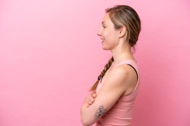 Genç beyaz kadın, pembe arka planda, yan pozisyonda izole edilmiş.