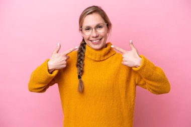 Pembe arka planda izole edilmiş beyaz bir kadın baş parmak hareketi yapıyor.