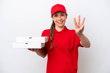 Pizza dağıtan kadın üniformalı beyaz arka planda izole edilmiş pizza kutuları alıyor mutlu ve parmaklarıyla üçe kadar sayıyor.