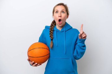 Beyaz arka planda basketbol oynayan beyaz tenli genç bir kadın parmak kaldırmayı düşünüyor.