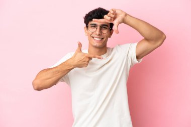 Arjantinli genç bir adam pembe arka planda izole edilmiş, odaklanmış bir yüz. Çerçeve sembolü