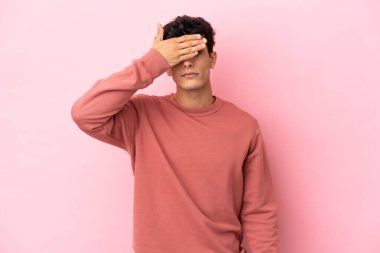 Arjantinli genç adam pembe arka planda izole edilmiş, gözlerini elleriyle kapatıyor. Bir şey görmek istemiyorum.