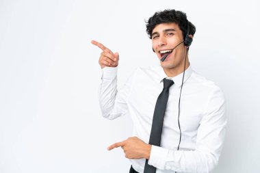 Tele pazarlamacı beyaz arka planda izole edilmiş bir kulaklıkla çalışıyor. Parmakla işaret ediyor ve bir ürün sunuyor.