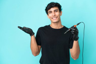 Dövme sanatçısı Arjantinli adam mavi arka planda izole edilmiş ve davet edilmek için elini yana uzatıyor.