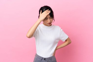 Genç Vietnamlı kadın pembe arka planda izole edilmiş, baş ağrısı var.