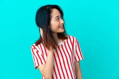 Genç Vietnamlı kadın mavi arka planda izole edilmiş bir fikir düşünüyor.