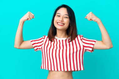 Mavi arka planda izole edilmiş genç Vietnamlı kadın güçlü bir jest yapıyor.