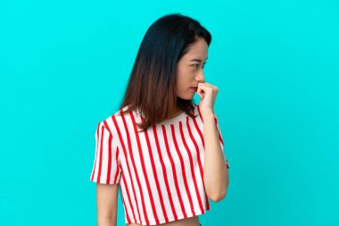 Genç Vietnamlı kadın mavi arka planda izole edilmiş. Şüpheleri var.