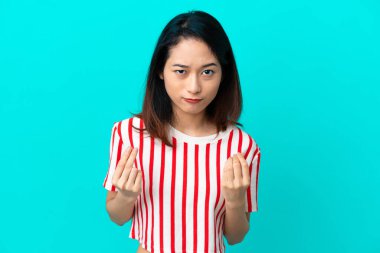 Genç Vietnamlı kadın mavi arka planda izole edilmiş para hareketi yapıyor ama mahvolmuş.