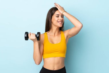 Mavi arka planda ağırlık kaldıran genç beyaz kadın bir şey fark etti ve çözüme niyetlendi.