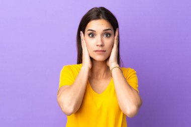 İzole edilmiş arka planda genç beyaz kadın hayal kırıklığına uğramış ve kulaklarını kapatmış.