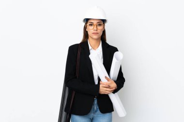 Miğferli, kafkasyalı genç bir kadın izole bir arka plan üzerinde planları tutuyor ve kollarını kavuşturuyor.