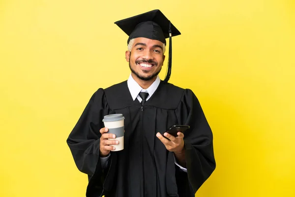 Νεαρός Απόφοιτος Πανεπιστημίου Κολομβιανός Άνδρας Απομονωμένος Κίτρινο Φόντο Κρατώντας Καφέ — Φωτογραφία Αρχείου