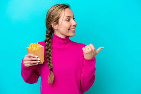 Young Caucasian Woman Holding Fried Chips Isolated Blue Background Pointing — Stock Fotó