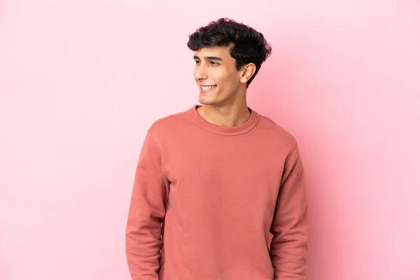 年轻的阿根廷男子在粉色背景上孤立无援 望着侧面 面带微笑 — 图库照片