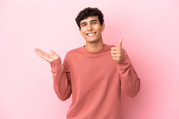 Mladý Argentinský Muž Izolovaný Růžovém Pozadí Drží Copyspace Imaginární Dlani — Stock fotografie