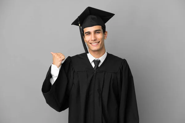 Jonge Argentijnse Universitair Afgestudeerde Geïsoleerd Grijze Achtergrond Wijzend Naar Zijkant — Stockfoto