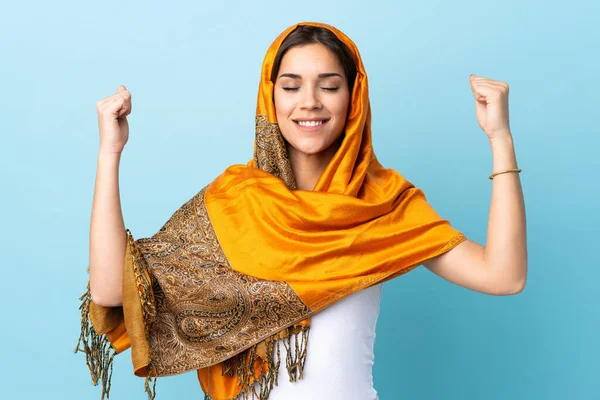年轻的摩洛哥女人穿着传统服装 蓝色背景 做着强有力的手势 — 图库照片