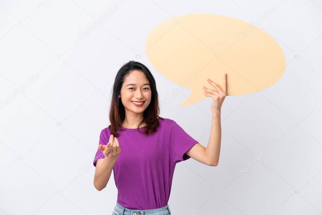 Young Vietnamese woman isolated on white background holding an empty speech bubble and doing coming gesture