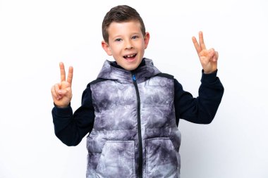 Beyaz arka planda izole edilmiş küçük çocuk iki eliyle zafer işareti gösteriyor.