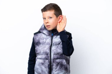 Beyaz arka planda izole edilmiş küçük bir çocuk bir şeyler dinlerken elini kulağına koyar.