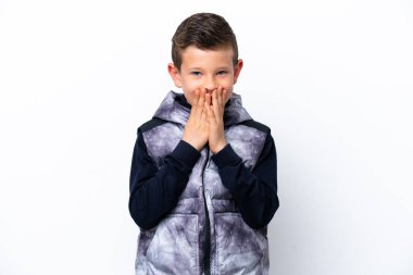 Beyaz arka planda izole edilmiş küçük bir çocuk mutlu ve gülümsüyor elleriyle ağzını kapatıyor.