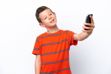 Beyaz arka planda izole edilmiş küçük bir çocuk selfie çekiyor.