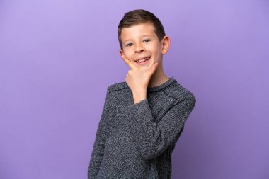 Küçük çocuk mor arka planda yalnız mutlu ve gülümsüyor.
