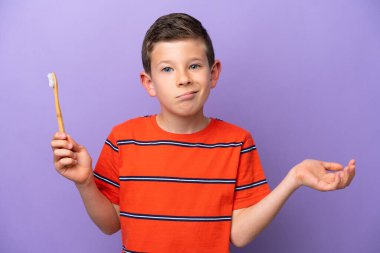 Mor arka planda dişlerini fırçalayan küçük çocuk omuzlarını kaldırırken şüpheyle hareket ediyor.