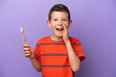 Mor arka planda dişlerini fırçalayan küçük çocuk ağzı açık bağırıyor.