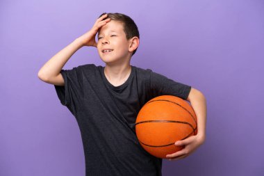 Mor arka planda izole edilmiş basketbol oynayan küçük çocuk çok gülümsüyor.