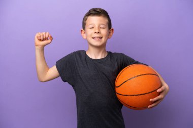Mor arka planda izole edilmiş basketbol oynayan küçük çocuk güçlü bir jest yapıyor.