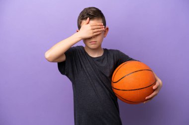 Mor arka planda izole edilmiş basketbol oynayan küçük çocuk gözleri elleriyle kapatıyor. Bir şey görmek istemiyorum.