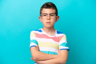 Mavi arka planda gözlüklü ve kolları bağlı küçük bir çocuk.