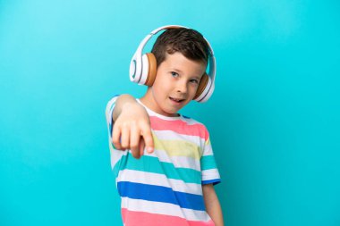 Küçük çocuk mavi arka planda izole edilmiş müzik dinliyor.