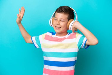 Küçük çocuk mavi arka planda izole edilmiş müzik ve dans dinliyor.