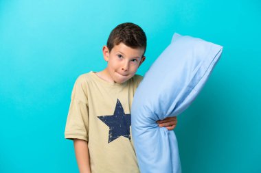 Mavi arka planda izole edilmiş pijamalı küçük bir çocuğun şüpheleri ve düşünceleri var.