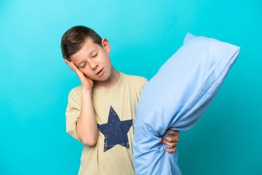 Mavi arka planda baş ağrısı olan pijamalı küçük bir çocuk.