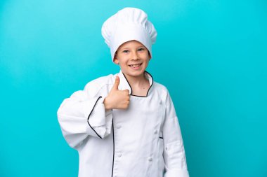 Küçük aşçı çocuk mavi arka planda izole edilmiş bir şekilde baş parmak hareketi yapıyor.