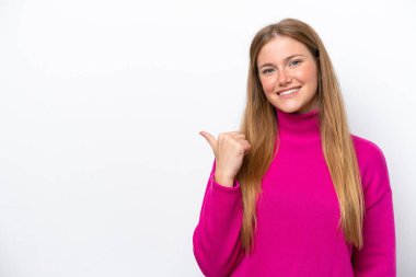 Beyaz arka planda izole edilmiş genç beyaz kadın bir ürünü sunmak için kenarı işaret ediyor.