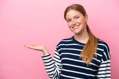 Pembe arka planda izole edilmiş genç beyaz kadın bir ilan vermek için avucunun içinde hayali bir fotokopi makinesi tutuyor.