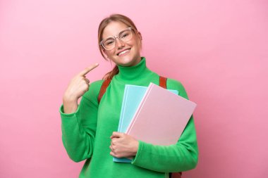 Pembe arka planda izole edilmiş genç beyaz bir bayan baş parmak hareketi yapıyor.