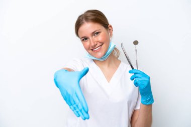 Beyaz arka planda izole edilmiş aletleri tutan beyaz dişçi kadın iyi bir anlaşma için el sıkışıyor