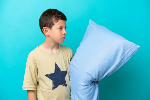 Mały Chłopiec Piżamie Odizolowany Niebieskim Tle Patrząc Boku — Zdjęcie stockowe