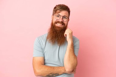 Kırmızımsı beyaz adam pembe arka planda izole edilmiş gülüyor.