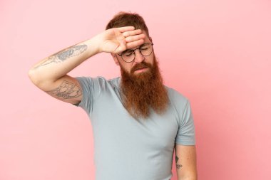 Kırmızımsı beyaz adam pembe arka planda izole edilmiş, yorgun ve hasta bir ifadeyle.