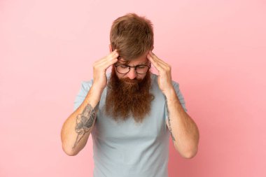 Kırmızımsı beyaz adam pembe arka planda baş ağrısı ile izole edildi.