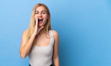 Genç Uruguaylı sarışın kadın izole edilmiş arka planda ağzı açık bağırıyor.