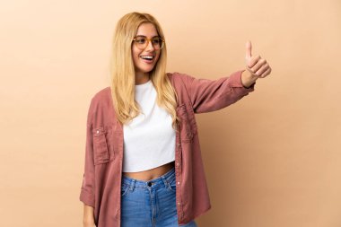 Genç Uruguaylı sarışın kadın, izole edilmiş geçmişinden dolayı baş parmak işareti yapıyor.