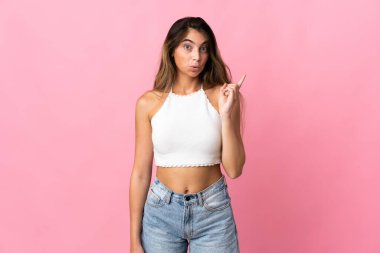 Pembe arka planda izole edilmiş genç beyaz kadın çözümü bulmak için parmağını kaldırıyor.